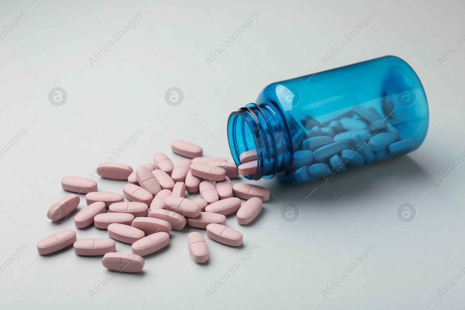 Photo of Vitamin pills and bottle on grey background, closeup