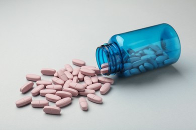 Vitamin pills and bottle on grey background, closeup