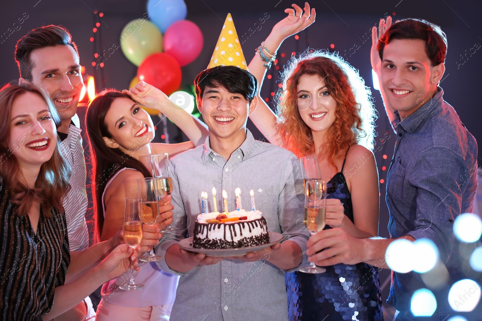 Photo of Young people celebrating birthday with cake in nightclub