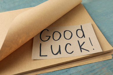 Sheet of paper with phrase GOOD LUCK on light blue wooden table, closeup