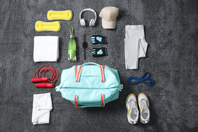 Flat lay composition with bag and sports items on grey carpet