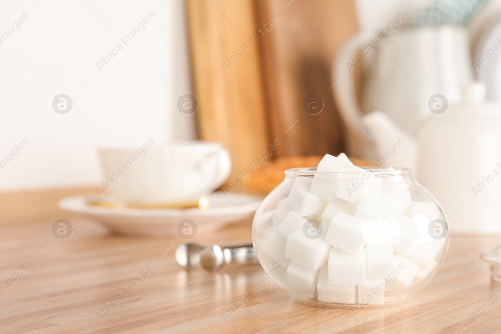 Photo of Glass bowl with white sugar cubes on wooden table