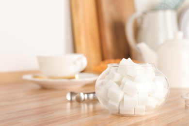 Photo of Glass bowl with white sugar cubes on wooden table