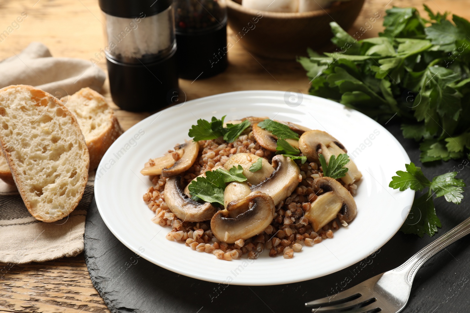 Photo of Tasty buckwheat with fresh parsley and mushrooms served on table, closeup