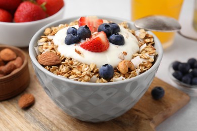 Photo of Tasty granola, yogurt and fresh berries in bowl on table, closeup. Healthy breakfast