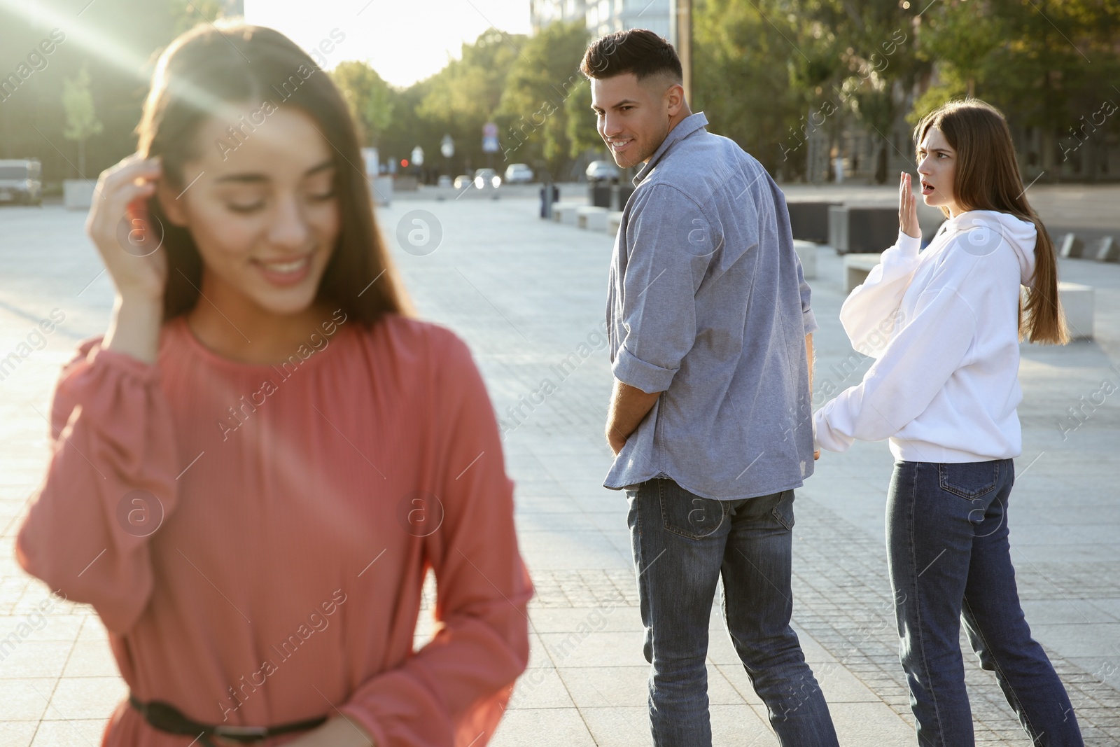 Photo of Disloyal man looking at another woman while walking with his girlfriend outdoors