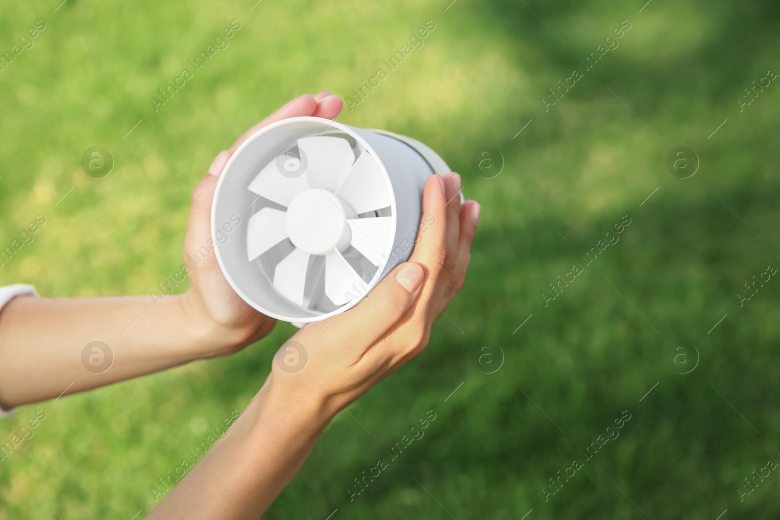 Photo of Woman holding portable fan outdoors on sunny summer day, closeup. Space for text