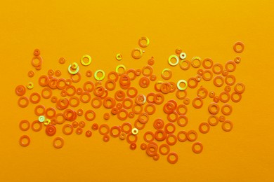 Shiny bright glitter on pale orange background, top view