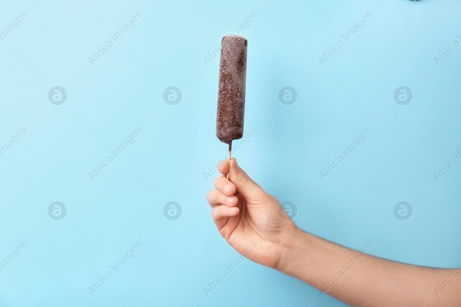 Photo of Man holding yummy ice cream on color background. Focus on hand