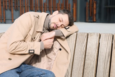 Photo of Tired man sleeping on bench outdoors. Space for text