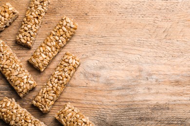 Delicious sweet kozinaki bars on wooden table, flat lay. Space for text