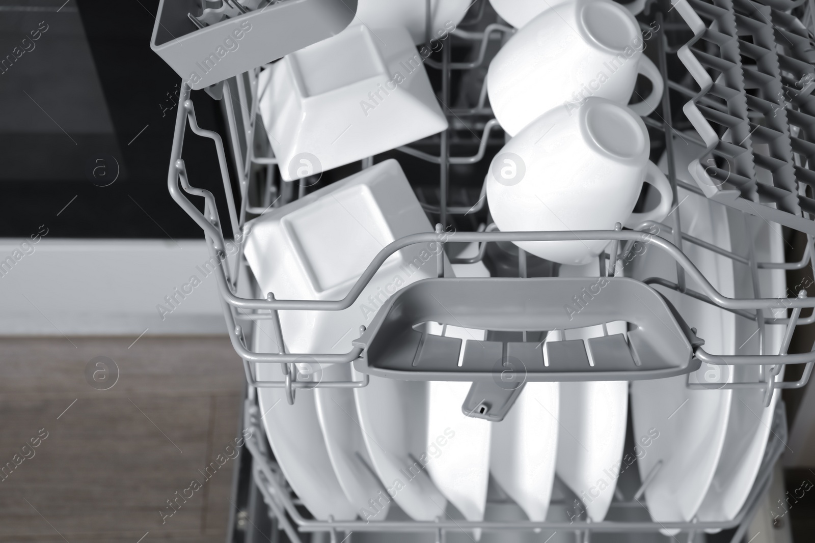 Photo of Open modern dishwasher with clean tableware, closeup