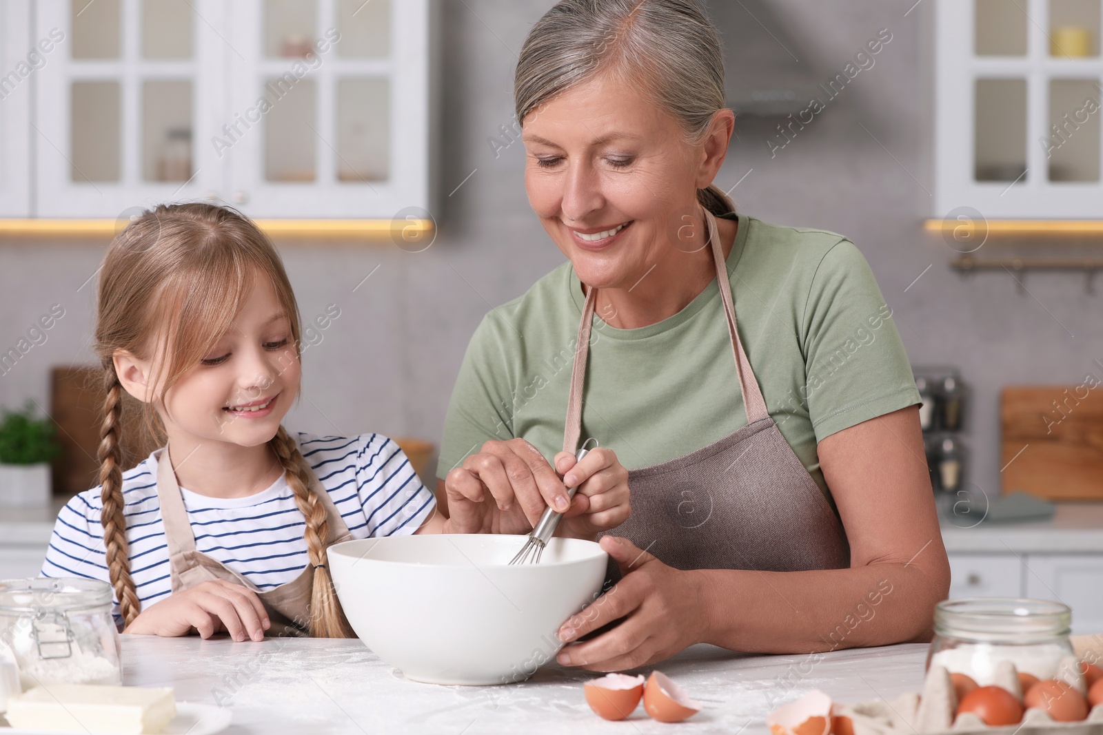 Photo of Happy grandmother with her granddaughter cooking together in kitchen