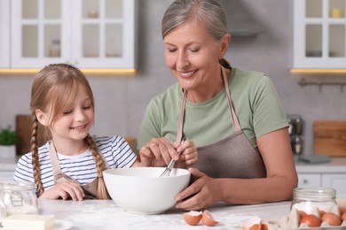 Photo of Happy grandmother with her granddaughter cooking together in kitchen