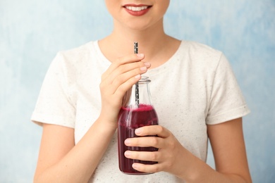 Woman with bottle of beet smoothie on light background, closeup