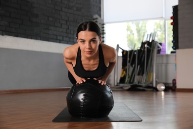 Photo of Sporty woman doing push up with medicine ball in modern gym