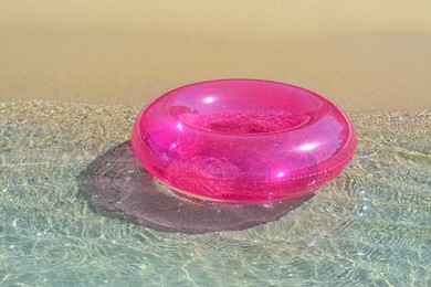 Bright inflatable ring on sandy beach near sea