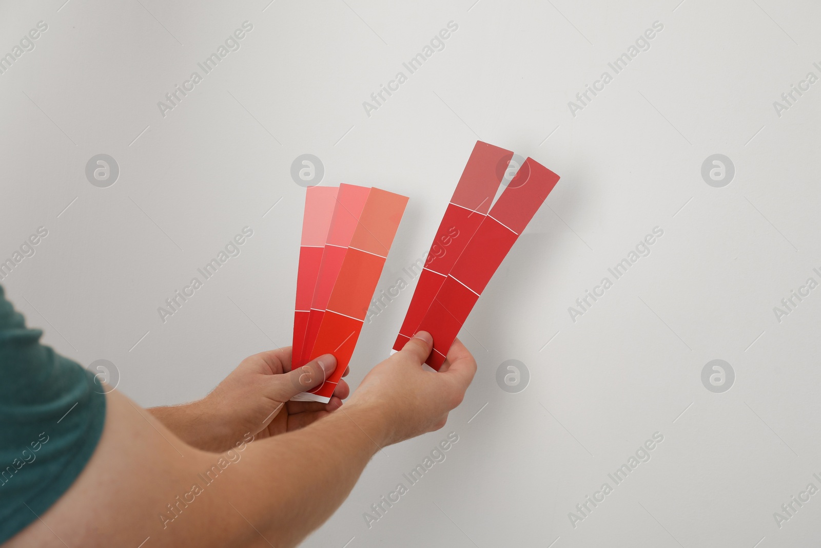 Photo of Man with palette choosing color for painting wall indoors, closeup. Interior design