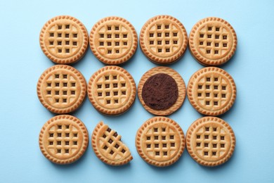 Tasty sandwich cookies with cream on light blue background, flat lay