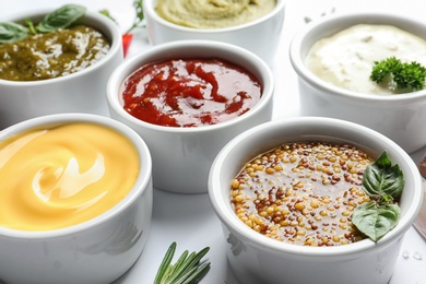 Bowls with different sauces on white background