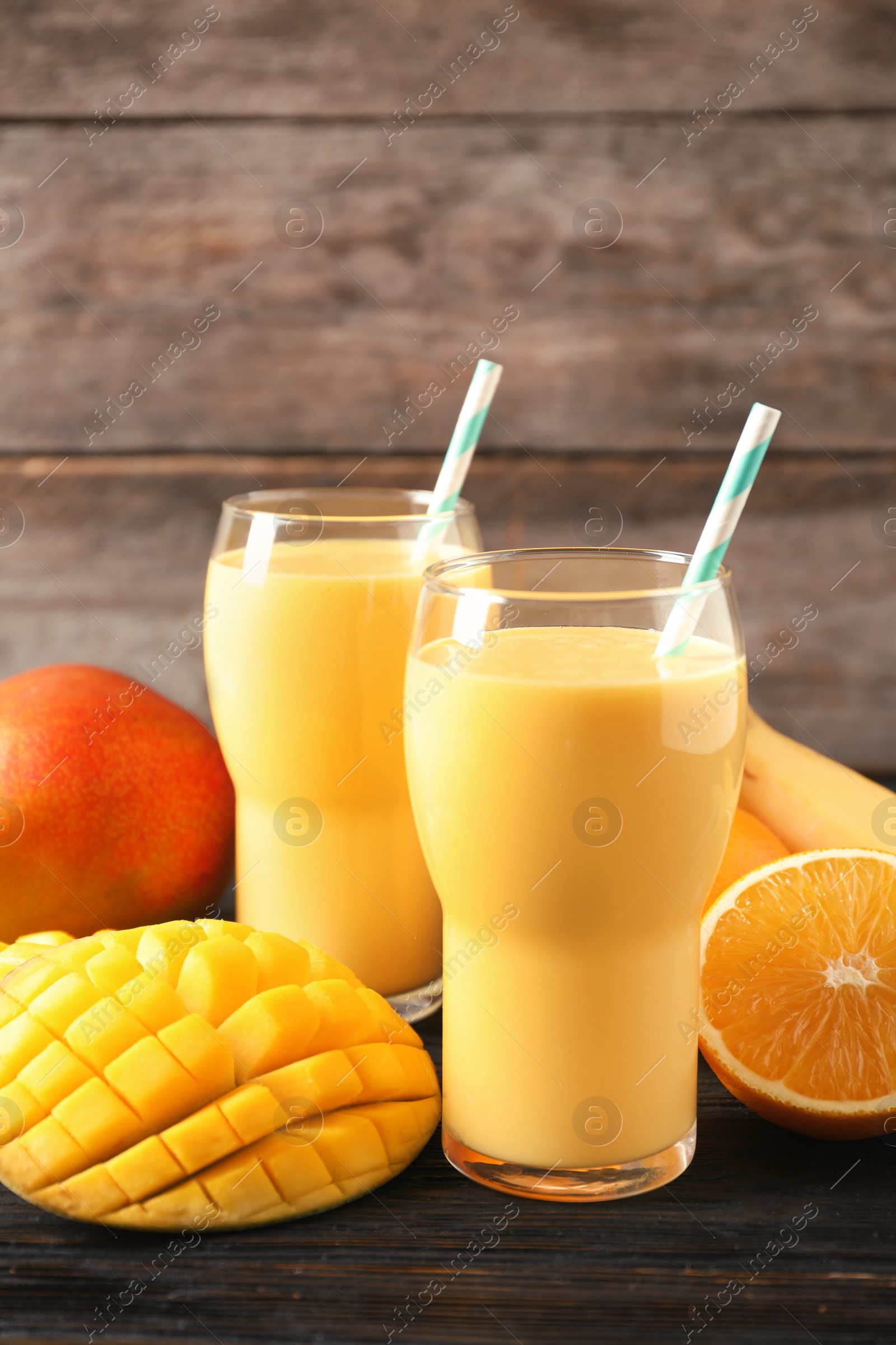 Photo of Tasty tropical drink with mango and fresh fruits on wooden table. Space for text