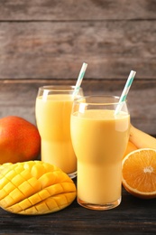 Tasty tropical drink with mango and fresh fruits on wooden table. Space for text