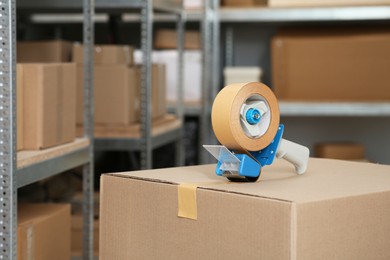 Photo of Taping cardboard box with adhesive tape dispenser indoors