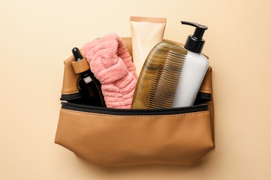 Preparation for spa. Compact toiletry bag with different cosmetic products on beige background, top view
