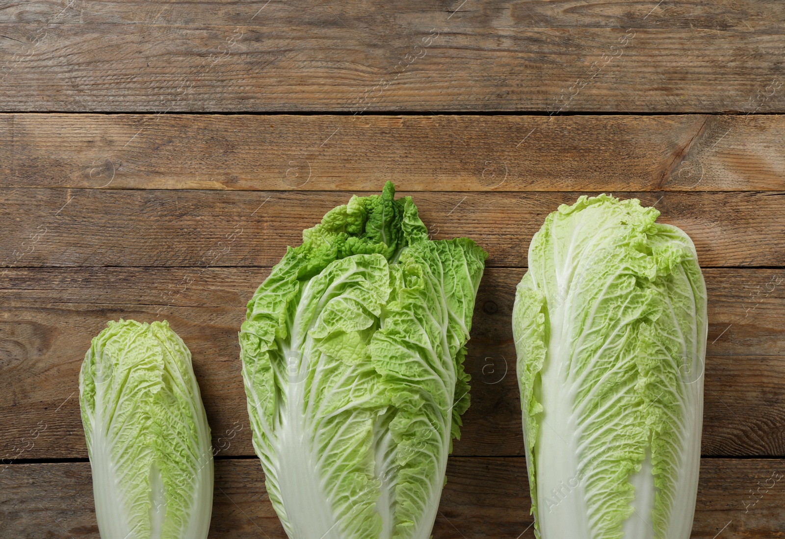 Photo of Fresh ripe Chinese cabbages on wooden table, fat lay. Space for text