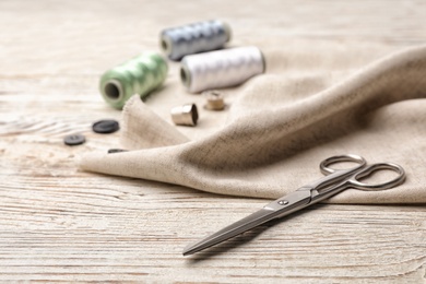 Photo of Composition with threads and sewing accessories on wooden background