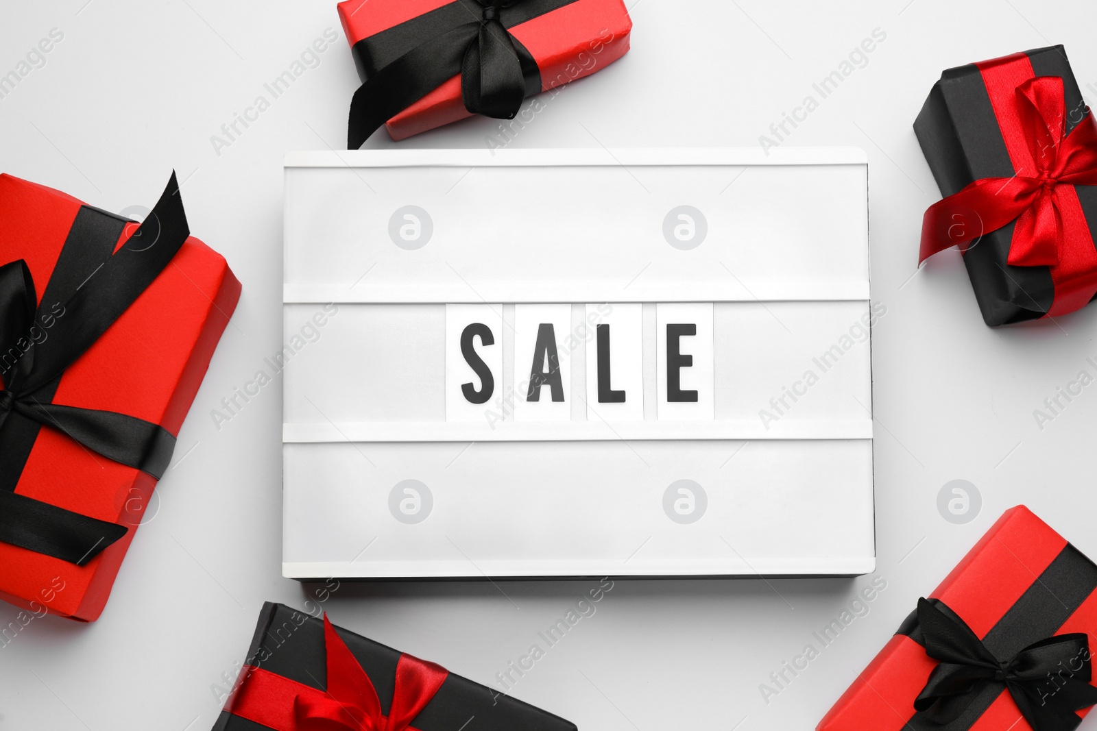 Photo of Light box with word Sale and gifts on white background, top view
