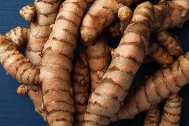 Many raw turmeric roots on blue table, flat lay