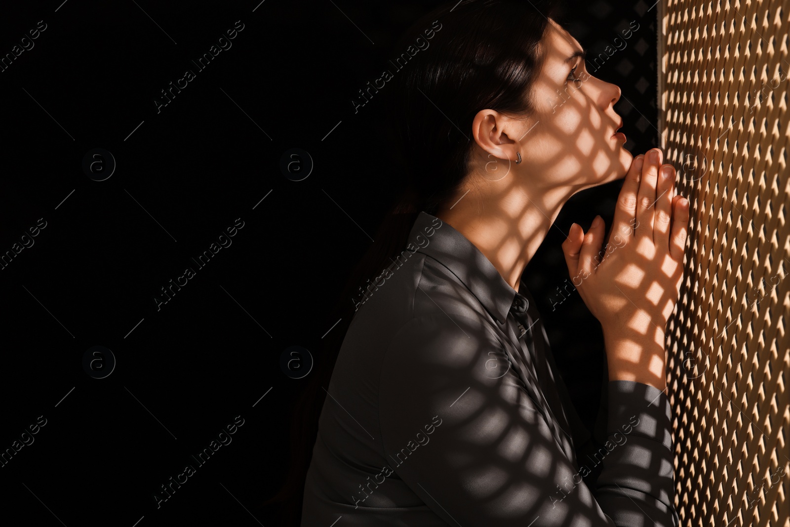 Photo of Woman praying to God during confession in booth, space for text