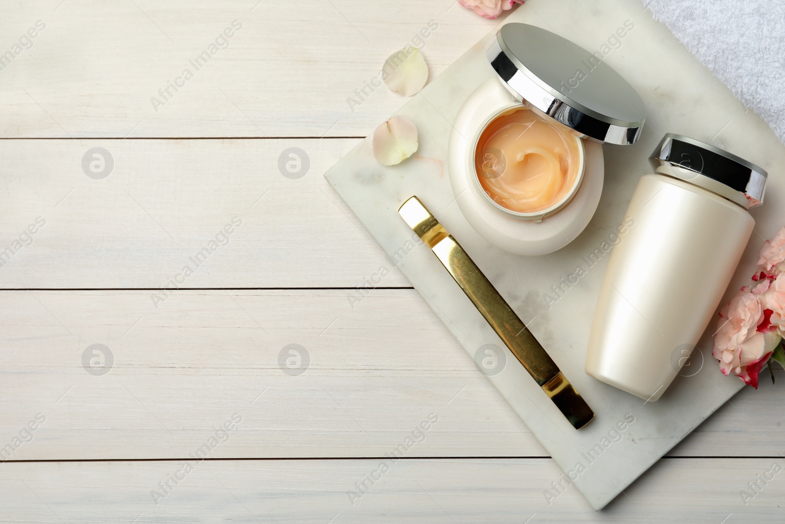 Photo of Hair care cosmetic products, beautiful flowers and towel on white wooden table, flat lay. Space for text