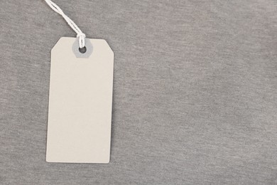 Photo of Cardboard tag on brown garment, top view. Space for text