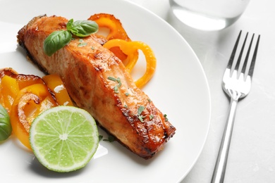 Photo of Tasty cooked salmon with vegetables on plate, closeup