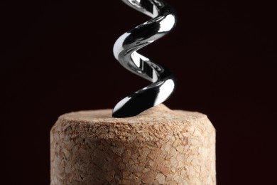 Photo of Corkscrew with cork against dark background, closeup