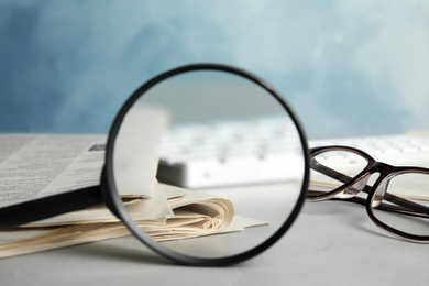 Photo of Looking through magnifying glass at newspapers, closeup. Job search concept
