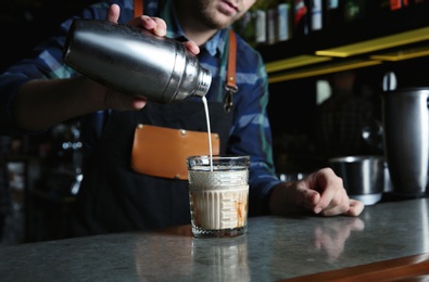 Photo of Barman making White Russian cocktail at counter in pub, closeup. Space for text