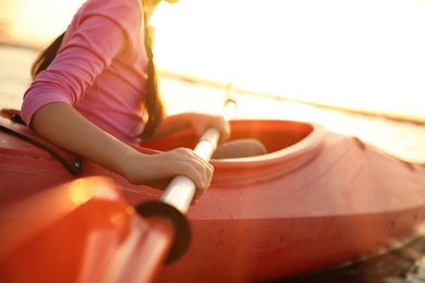 Photo of Little girl kayaking on river at sunset, closeup. Summer camp activity