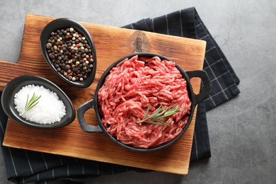 Photo of Raw ground meat in bowl and spices on grey table, top view