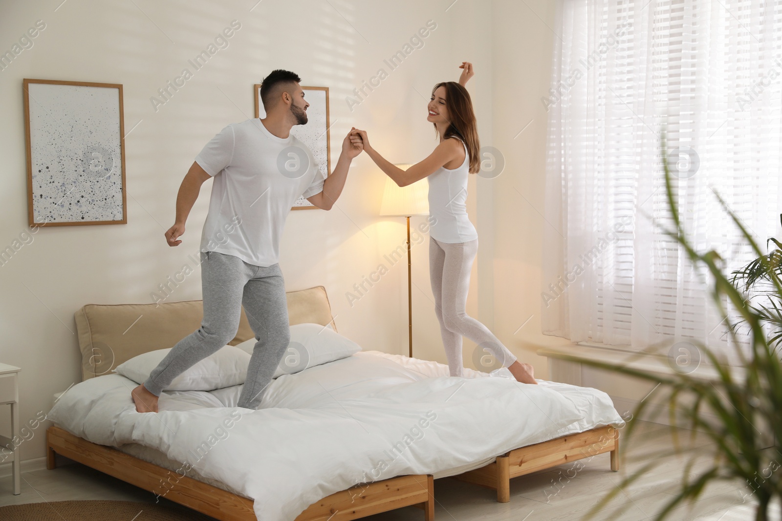 Photo of Lovely young couple dancing on bed at home