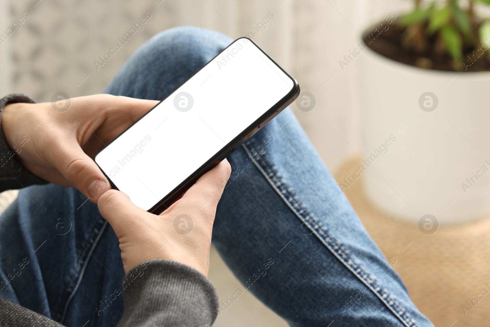 Photo of Man using smartphone with blank screen indoors, closeup. Mockup for design