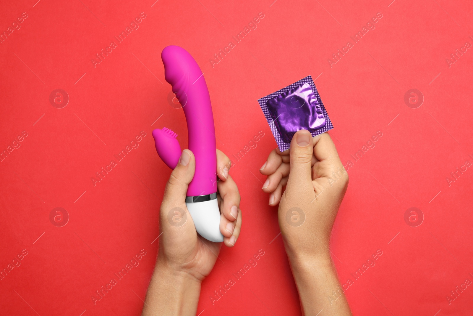 Photo of Woman with vibrator and condom on red background, top view. Sex game