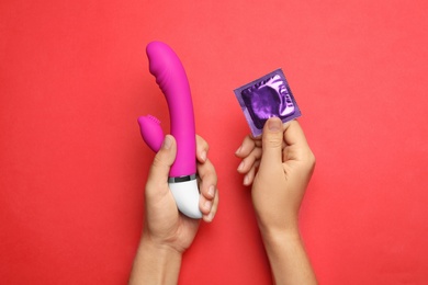 Woman with vibrator and condom on red background, top view. Sex game