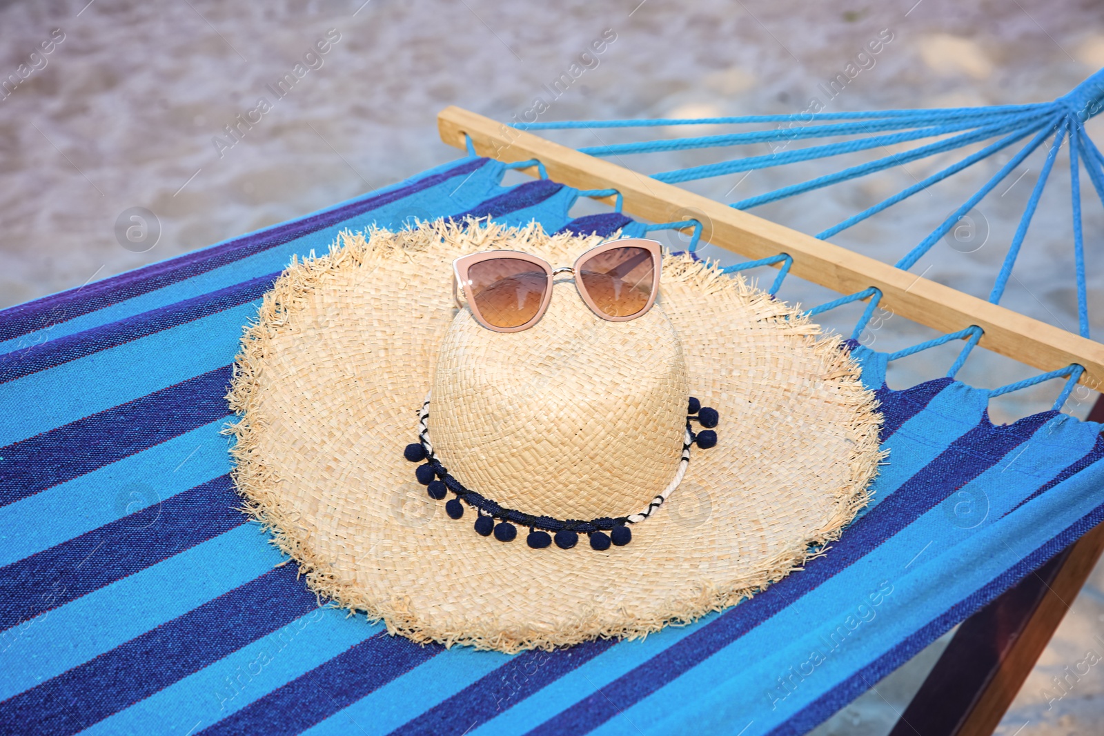 Photo of Comfortable hammock with straw hat and sunglasses at seaside