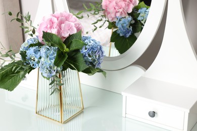 Photo of Beautiful hortensia flowers in vase on dressing table indoors