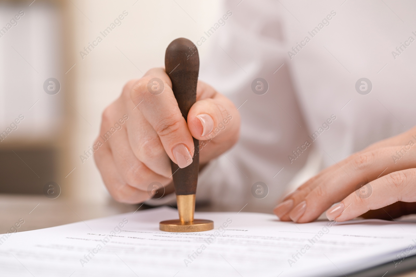 Photo of Woman stamping document at table, closeup view