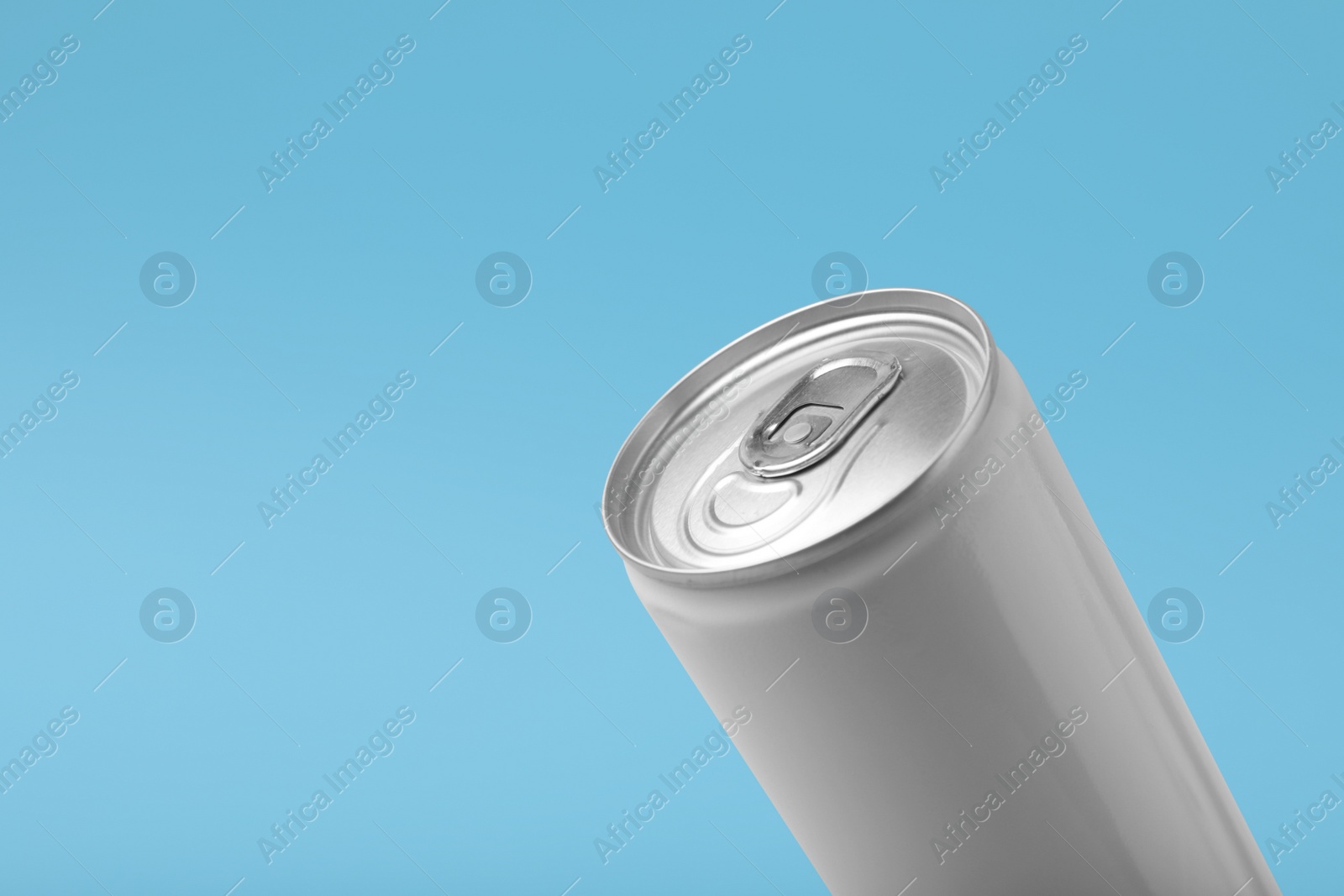 Photo of Can of energy drink on light blue background, closeup. Space for text