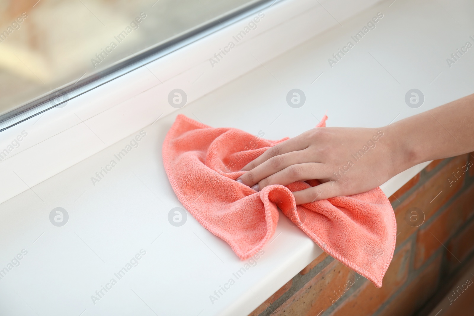 Photo of Woman cleaning window sill with cloth, closeup